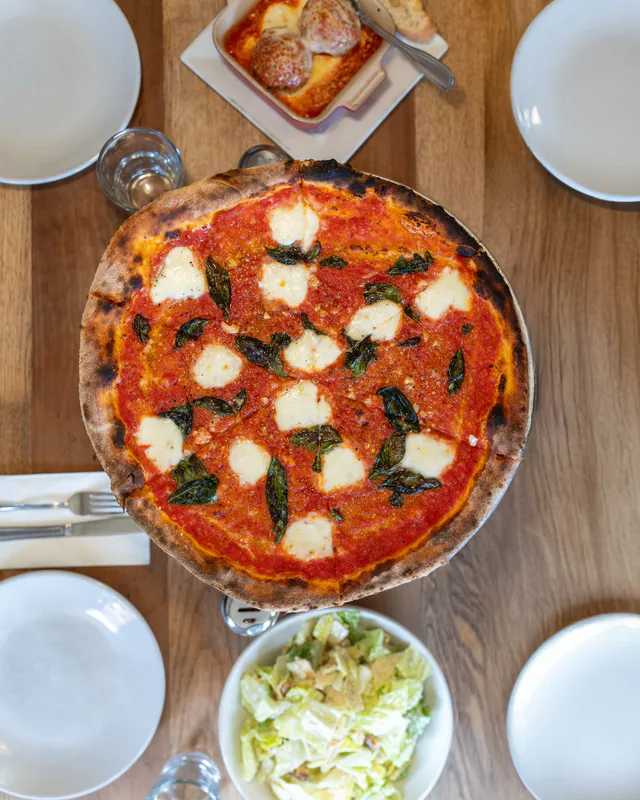 A Margherita pizza with basil, shot from above on a table at 1943 Pizza Bar in Greenport