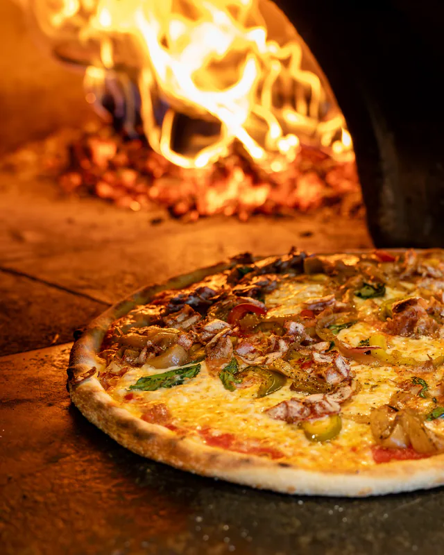 A pizza in front of the flames of the wood-fired oven at 1943 Pizza Bar, Greenport