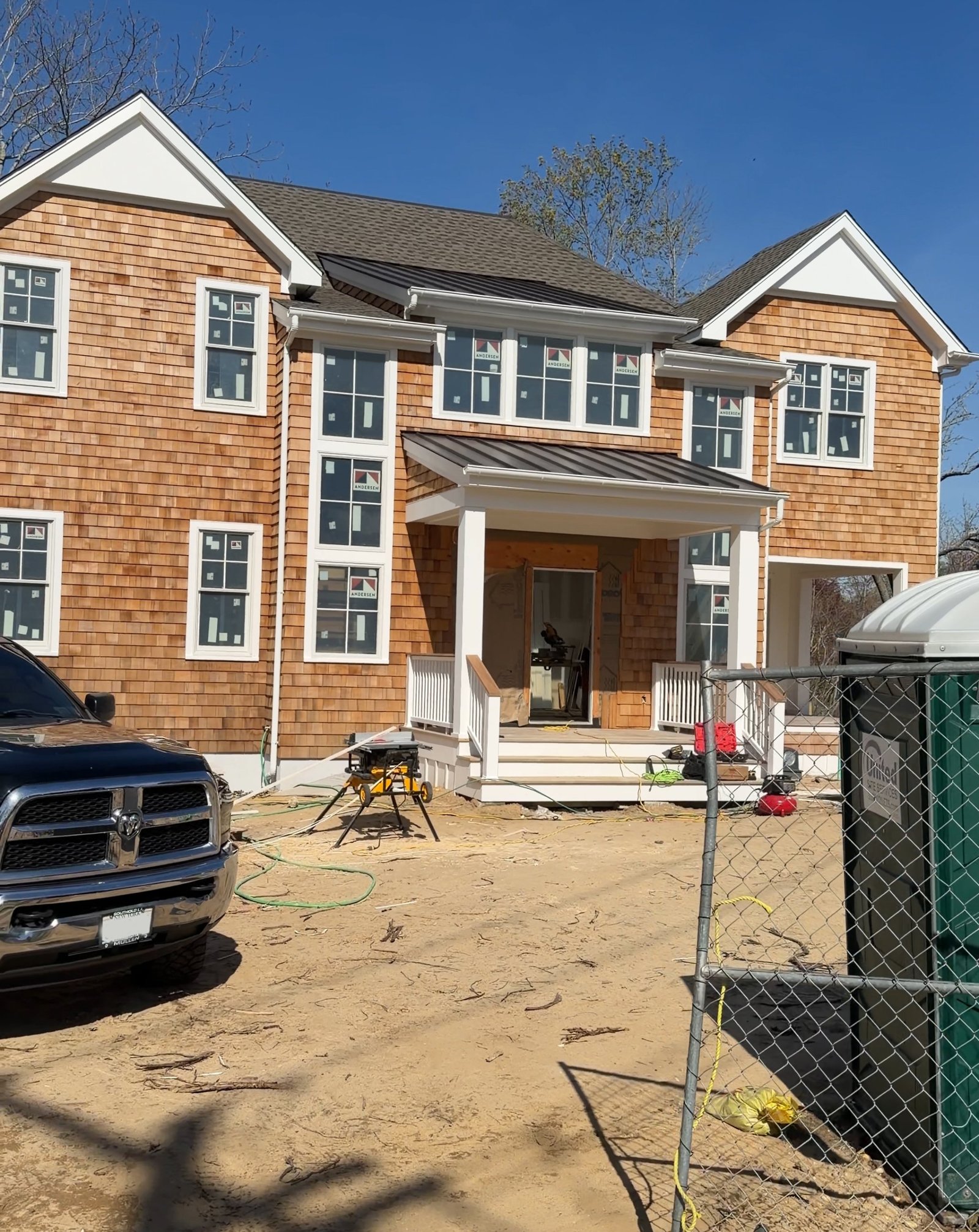 The same house earlier in the project, a working construction site with a dirt yard and fencing.