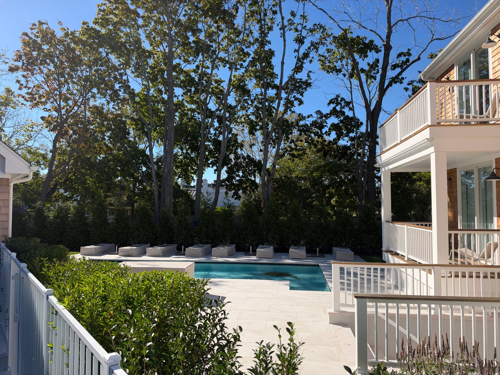The pool and bluestone patio behind the bed and breakfast, framed by hedges and mature trees.
