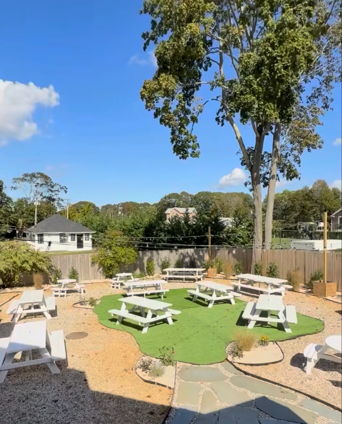 The Galley backyard by day, with picnic tables on gravel around a turf lawn.