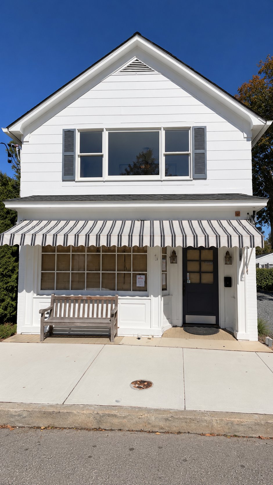 The white two story Mill Road building with a striped awning over the storefront.