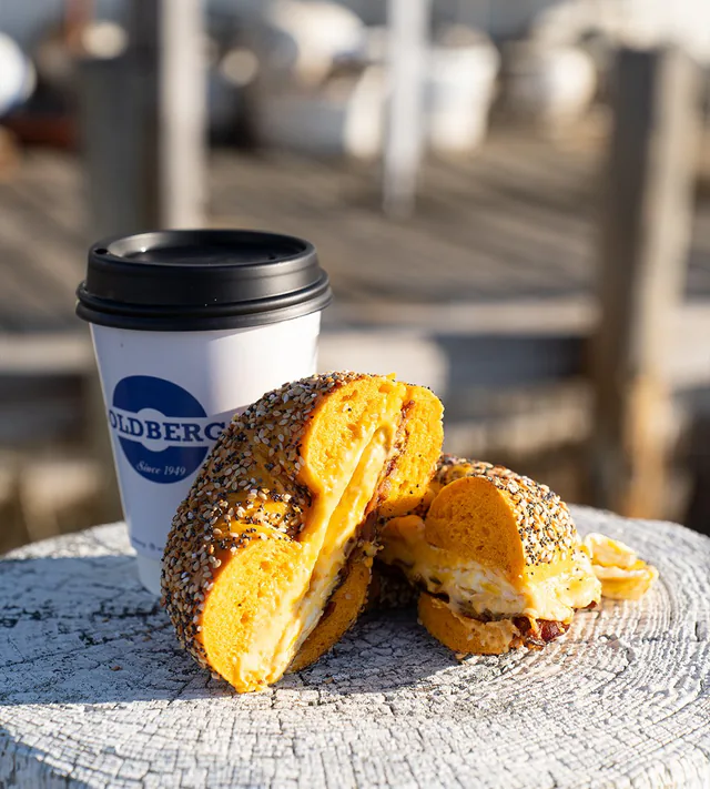 A Goldberg’s Famous Bagels sandwich and coffee on a dock piling in Greenport