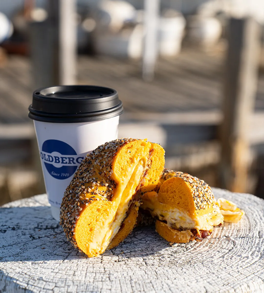 A Goldberg’s Famous Bagels sandwich and coffee on a dock piling in Greenport