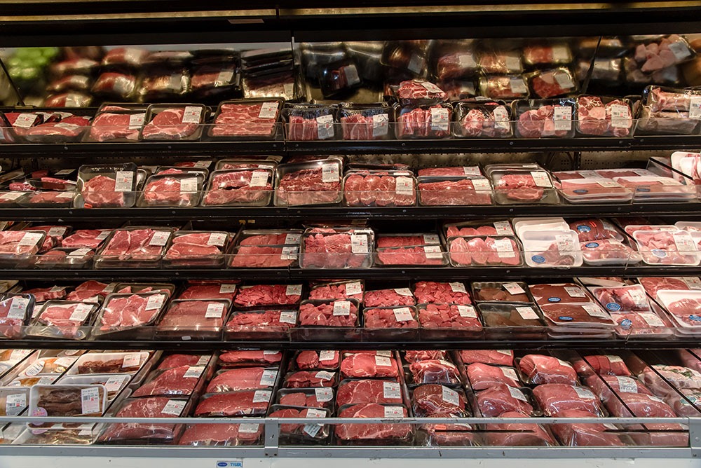 Shelves of packaged steaks and cuts of beef in a supermarket meat case.