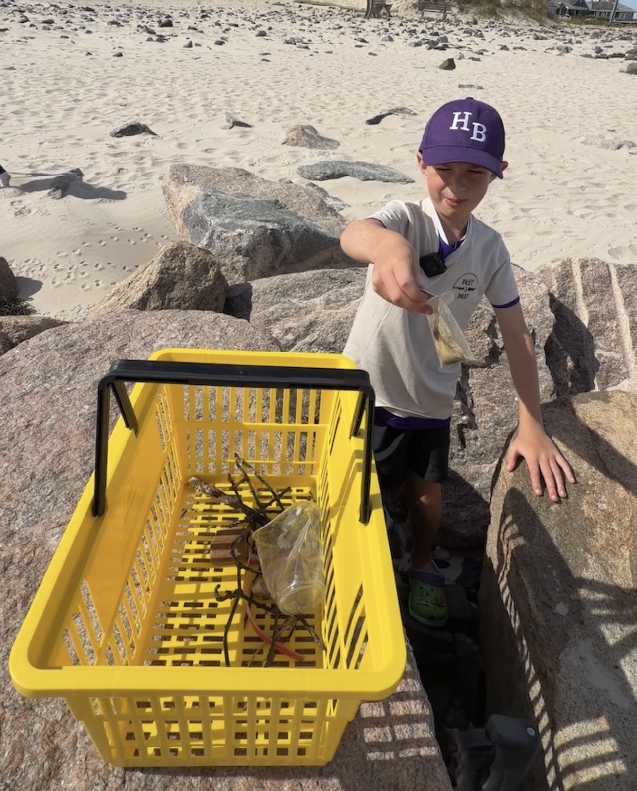 Luca dropping trash from the jetty rocks into a yellow Relic basket